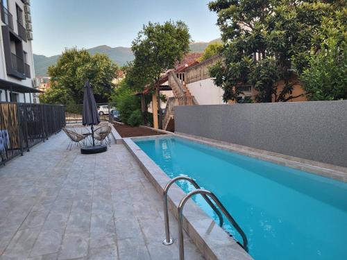 a swimming pool with an umbrella and chairs next to a building at Mini Condos® 28DL - 1 bed condo, 2 min to the sea in Tivat