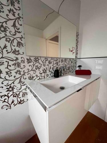 een badkamer met een witte wastafel en een spiegel bij Casa Capelute in Udine