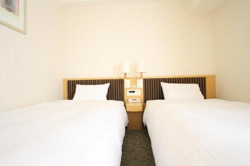 two beds sitting next to each other in a room at KOKO HOTEL Sendai Station South in Sendai