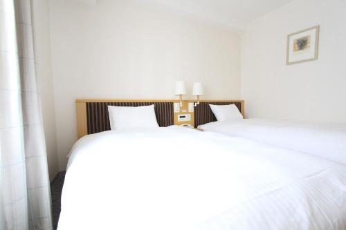 two beds sitting next to each other in a bedroom at KOKO HOTEL Sendai Station South in Sendai