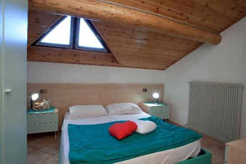 VERDELAGO Appartamenti e CASA CRY في ليفينو: غرفة نوم عليها سرير ومخدة حمراء