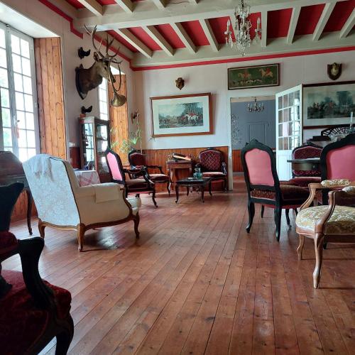 sala de estar con sillas y mesas y suelo de madera en Domaine de Frély, en Pouzauges
