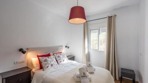 una camera da letto con un letto con lenzuola bianche e cuscini rossi di Casa Rio Grande 2 Tolox by Ruralidays a Tolox