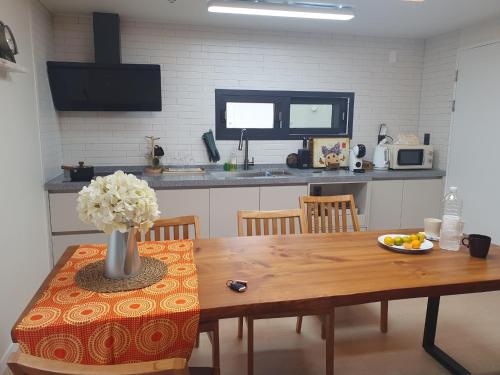 eine Küche mit einem Tisch, auf dem eine Blumenvase steht in der Unterkunft Jois House in Jeju-do