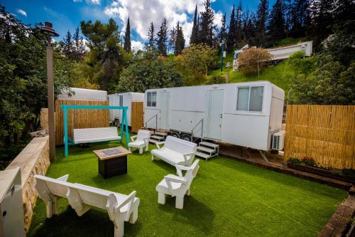 an rv backyard with chairs and tables and a lawn at אירוח יער השלום in Jerusalem