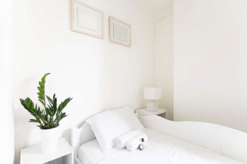 ein weißes Schlafzimmer mit einem weißen Bett und einer Pflanze in der Unterkunft Luxury modern two bedroom duplex by Roland Garros in Paris