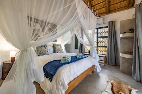 a bedroom with a bed with a mosquito net at Blue Goose Bush Retreat in Marloth Park
