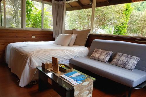 um quarto com uma cama, um sofá e janelas em Tomi House em Hengshan
