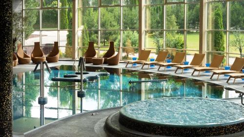 una piscina con sedie e un tavolo in un edificio di Harmony Park Hotel & SPA a Prienai