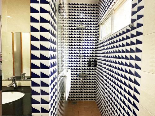 y baño con lavabo y paredes de azulejos azules y blancos. en Deng Mei Homestay, en Hengshan
