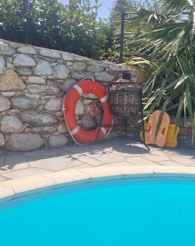 a red life preserver sitting next to a stone wall at The Cocoon and olives Hut in Koropi