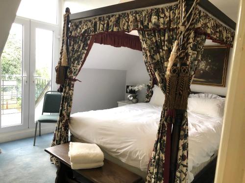 a bedroom with a canopy bed with a window at Margaret's Manor in Birchington