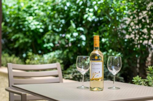 a bottle of wine sitting on a table with two wine glasses at Helion Apartments in Gouvia