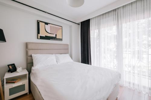ein Schlafzimmer mit einem weißen Bett und einem großen Fenster in der Unterkunft Chic Flat w Balcony 5 min to Moda Coast in Kadikoy in Istanbul