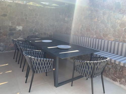 a black table with chairs and plates on it at Miss Valentina-Modern Stone Villa in Aegina in Aegina Town