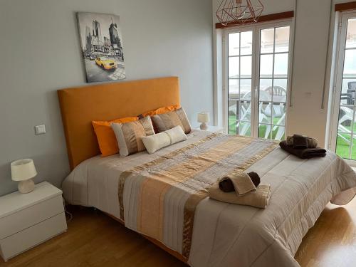 1 dormitorio con 1 cama grande con almohadas de color naranja en Peixinho Magnifique Appartement en Marinha Grande