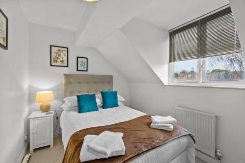 a bedroom with a bed with blue pillows and a window at Free Parking Near Shelly Beach Holiday Home in Exeter