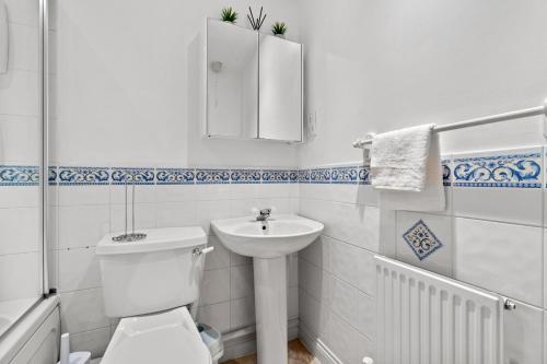 a white bathroom with a toilet and a sink at Free Parking Near Shelly Beach Holiday Home in Exeter