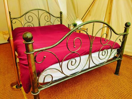 a metal bed with a pink blanket on it at Battle Pods and Bells Glamping in Battle