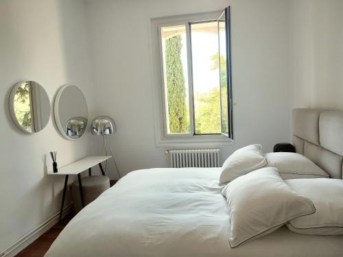 a white bedroom with a large bed and a window at Bastide Castella in Montpellier