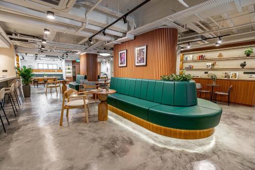 a lobby with a green couch and tables and chairs at Weave Suites - Midtown in Singapore