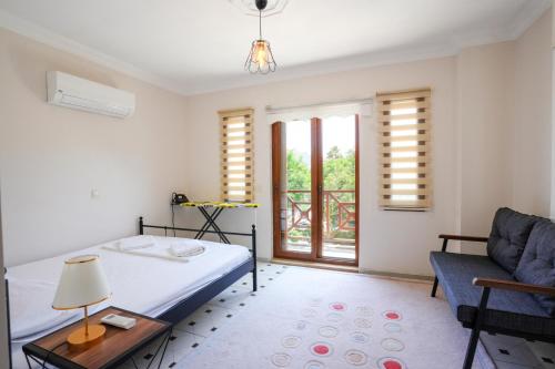 a bedroom with a bed and a couch and a window at Villa w Pool and Balcony 3 min to Dalyan River in Ortaca