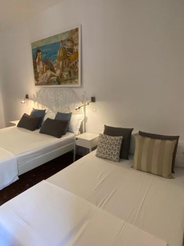 サレルノにあるCasa Castagnaの壁に絵画が描かれた客室内の白いベッド2台