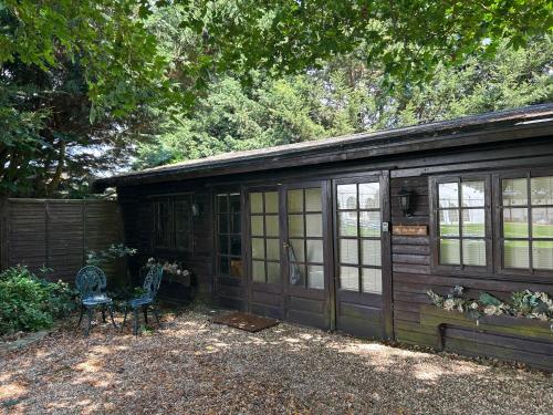 a wooden cabin with a bench and a chair at Lily Pad by Paymán Club in Royston