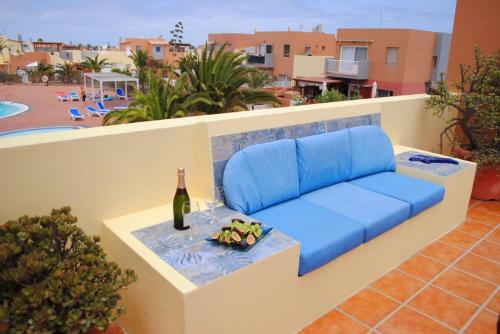 a blue couch on a balcony with a bottle of wine at Casa Leon Fuerteventura in Corralejo