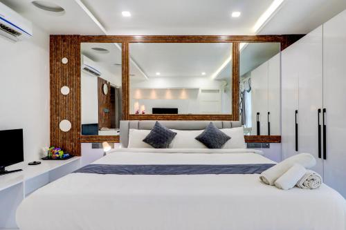 a bedroom with a large white bed and a tv at Hotel Brundavan International Guntur in Guntūr