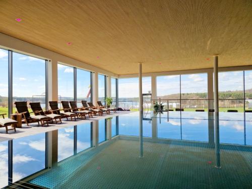 a large building with a pool with chairs and windows at Bio-Seehotel Zeulenroda in Zeulenroda