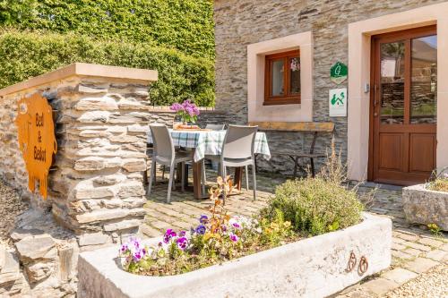 a stone house with a table and chairs and flowers at Gîte Bed & Bedot in Fauvillers