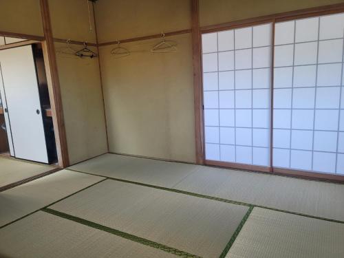 an empty room with two windows and a door at 하루카오후나에 민숙 in Tsushima