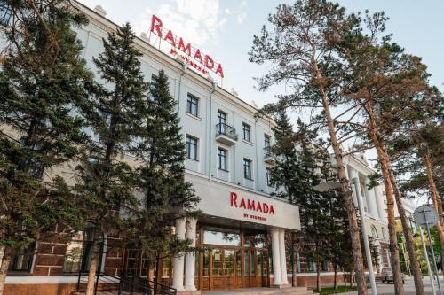 a white building with a red sign on it at Ramada by Wyndham Astana in Astana