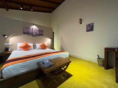 a bedroom with a bed with orange pillows and a table at Cloud Nine Wilpattu by Aaradhya in Wilpattu