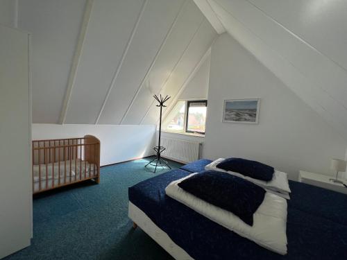 a bedroom with a bed and a crib in a attic at Hello Zeeland - Vakantiehuis Stern 207 in Breskens
