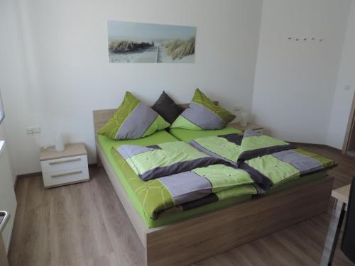 a bedroom with a bed with green sheets and pillows at Pension am Kirchberg in Wehringen