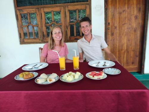 un hombre y una mujer sentados en una mesa con comida en Sigiri Green Shadow Homestay en Sigiriya