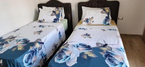 two beds in a room with blue flowers on them at Plage des nation 2 bedroom 100 mètre to the beach with huge pool 