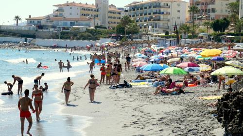 a crowd of people on a beach with umbrellas at Apartamentos StarNerja II in Nerja