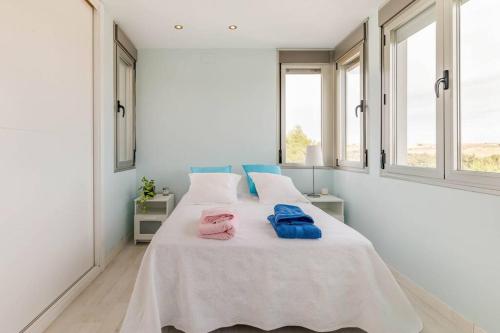 Oasis en Madrid con 4HB, 5 baños y Piscina Lujosa! في Villanueva del Pardillo: غرفة نوم بيضاء مع سرير عليه مناشف