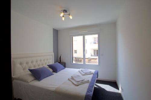 - une chambre dotée d'un lit blanc avec des oreillers bleus et d'une fenêtre dans l'établissement Krystal Palace B, à Beausoleil