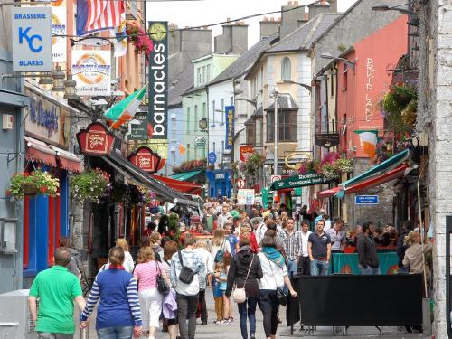 a crowd of people walking down a busy city street at Flannery's Hotel in Galway