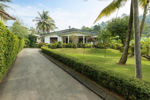 una casa con palmeras y un camino de entrada en Surveyor's Residence Bungalow, en Kandy