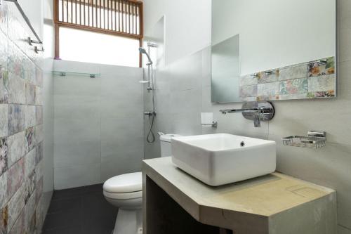 a white bathroom with a sink and a toilet at Surveyor's Residence Bungalow in Kandy