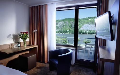 a hotel room with a desk and a view of a balcony at Hotel Villa am Rhein in Andernach