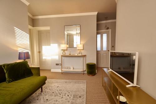 a living room with a green couch and a mirror at Lovely 2-bedroom apartment in Shoreditch in London