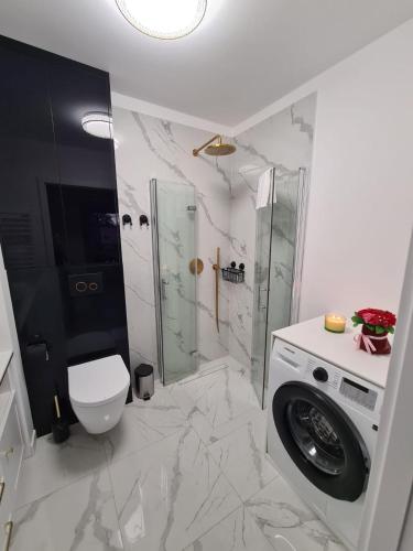 a bathroom with a shower and a washing machine at Modrzewiowy Zakątek in Augustów