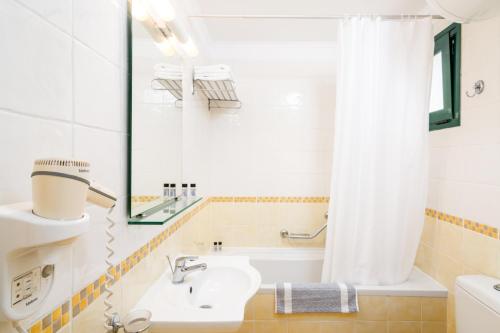 a bathroom with a sink and a tub and a shower curtain at Helion Resort in Gouvia