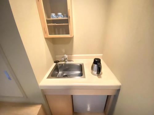 a sink in a small bathroom with a cupboard at Shikaribetsu Kohan Onsen Hotel Fusui in Shikaoi